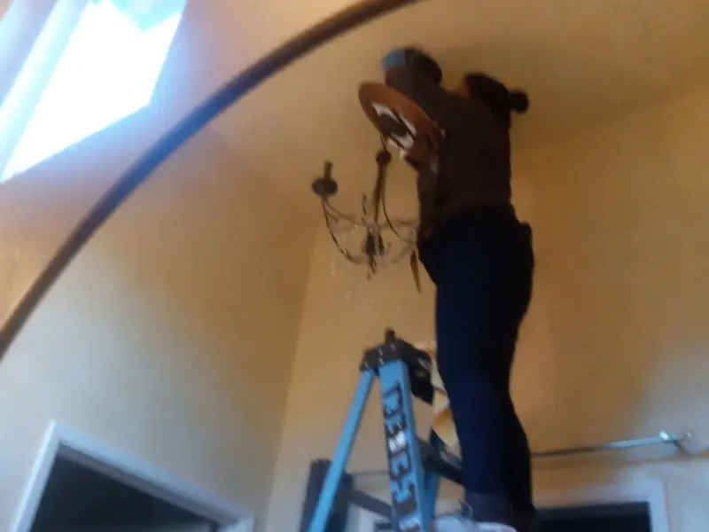 Electrician installing a chandelier in a Ulster residence
